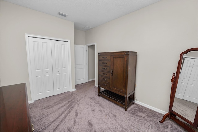 carpeted bedroom with a textured ceiling and a closet