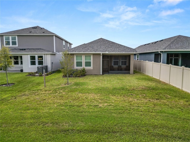 rear view of house with a sunroom, central AC unit, and a yard