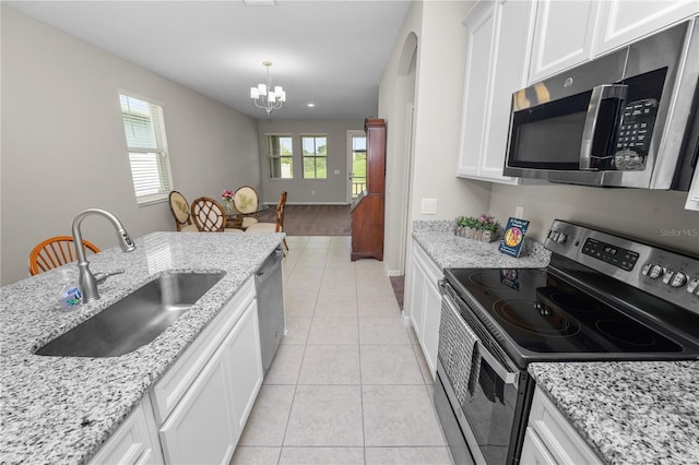 kitchen with stainless steel appliances, sink, light tile patterned floors, a notable chandelier, and white cabinets