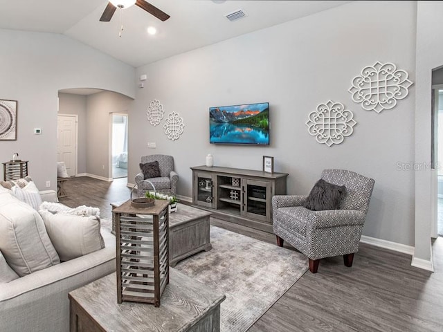 living room with ceiling fan, dark hardwood / wood-style floors, and vaulted ceiling