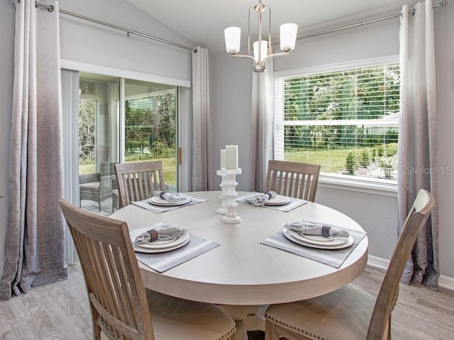 dining area featuring light hardwood / wood-style flooring, lofted ceiling, and a notable chandelier