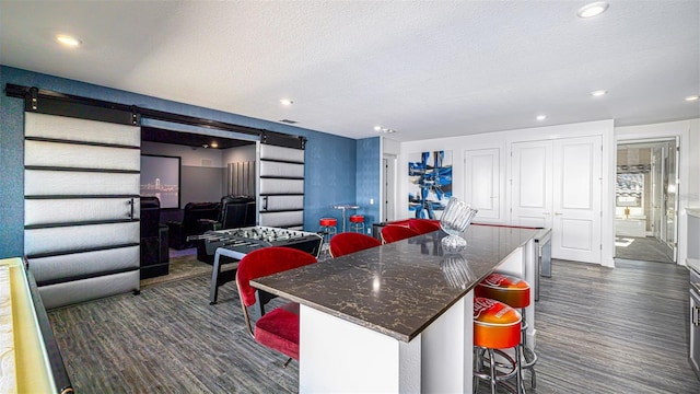 kitchen featuring a kitchen breakfast bar, a barn door, a center island, and a textured ceiling