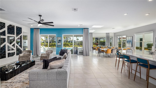 tiled living room with a wealth of natural light, ceiling fan, and a textured ceiling