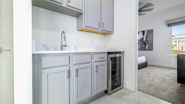 kitchen with gray cabinets, light colored carpet, wine cooler, and sink