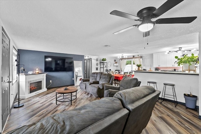 living room with ceiling fan, hardwood / wood-style floors, and a textured ceiling