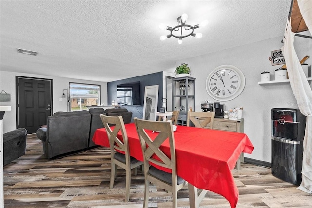 dining area featuring a textured ceiling, a chandelier, and hardwood / wood-style floors