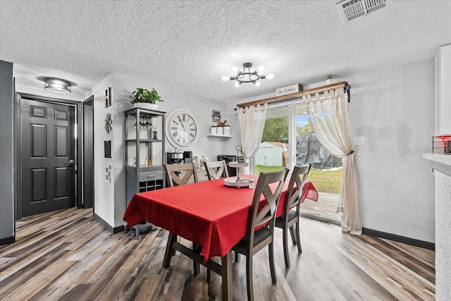 dining room featuring wood-type flooring, a textured ceiling, and a chandelier