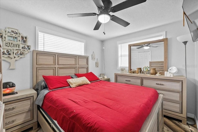 bedroom with a textured ceiling, ceiling fan, and dark wood-type flooring