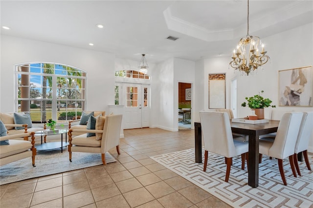 tiled dining area with ornamental molding, a raised ceiling, and a notable chandelier