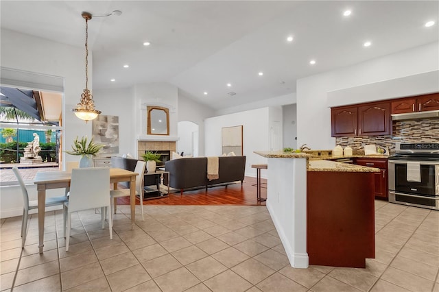 kitchen with lofted ceiling, a tile fireplace, pendant lighting, decorative backsplash, and stainless steel electric stove