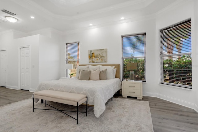 bedroom featuring a raised ceiling, crown molding, and hardwood / wood-style flooring