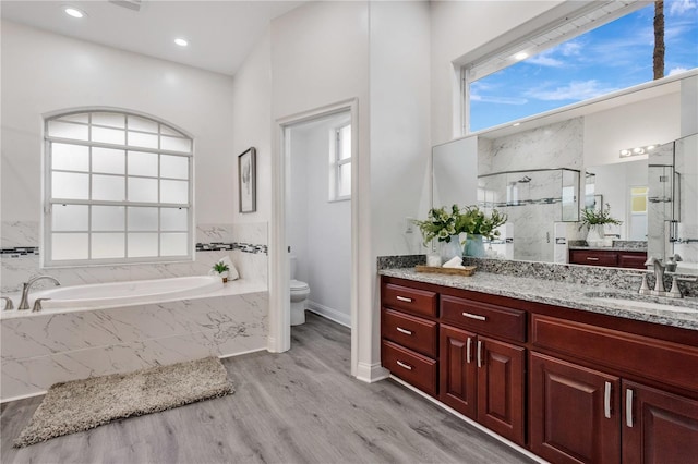 full bathroom with hardwood / wood-style flooring, toilet, vanity, and separate shower and tub