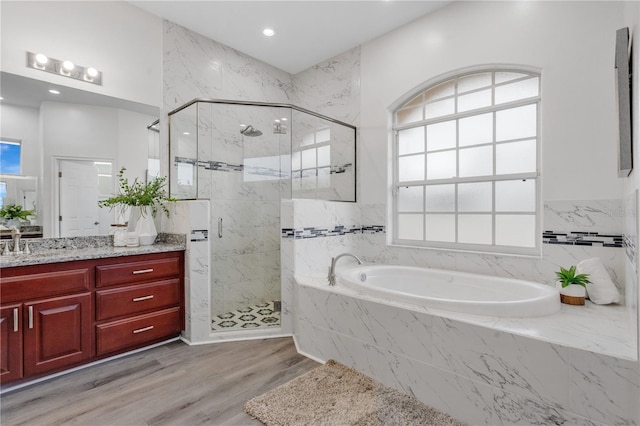 bathroom with plus walk in shower, a healthy amount of sunlight, hardwood / wood-style flooring, and vanity