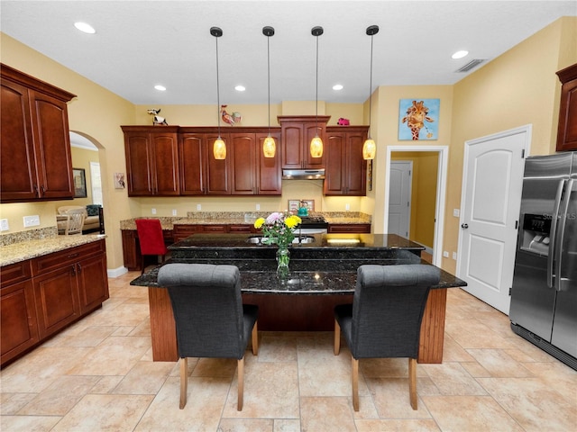 kitchen featuring a kitchen bar, stainless steel fridge with ice dispenser, dark stone countertops, and a center island