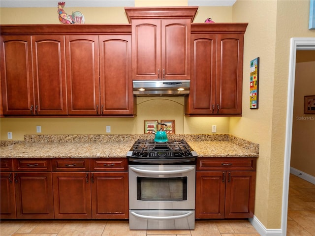 kitchen with stainless steel range with gas stovetop, light tile patterned floors, and light stone counters