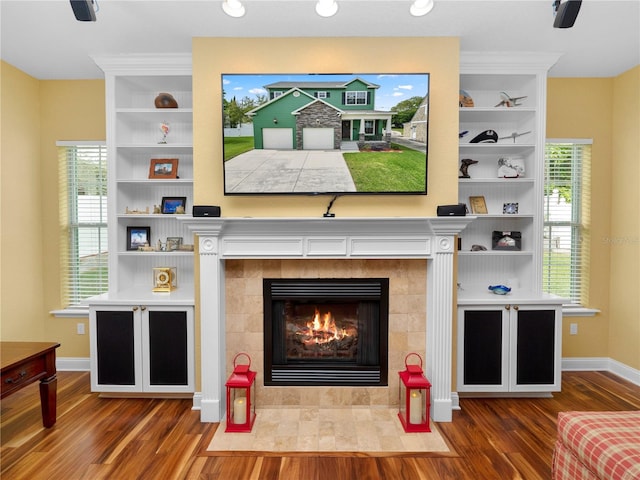 interior space with wood-type flooring, built in features, and a tiled fireplace