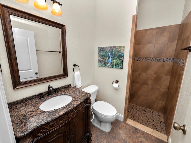 bathroom with vanity, toilet, and a tile shower