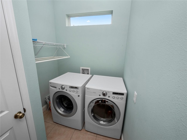 laundry area with washing machine and clothes dryer and light tile patterned floors