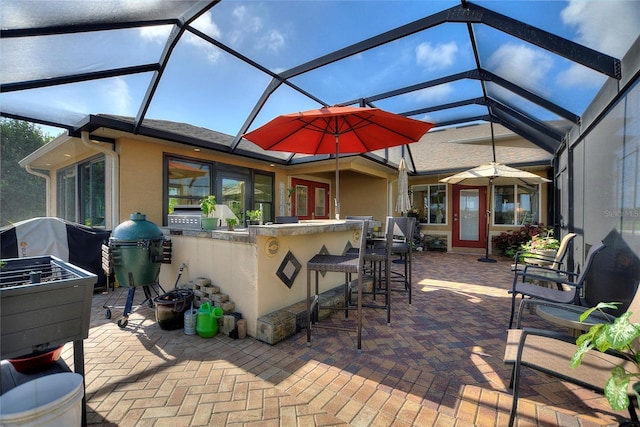 view of patio / terrace featuring grilling area, exterior bar, exterior kitchen, and a lanai