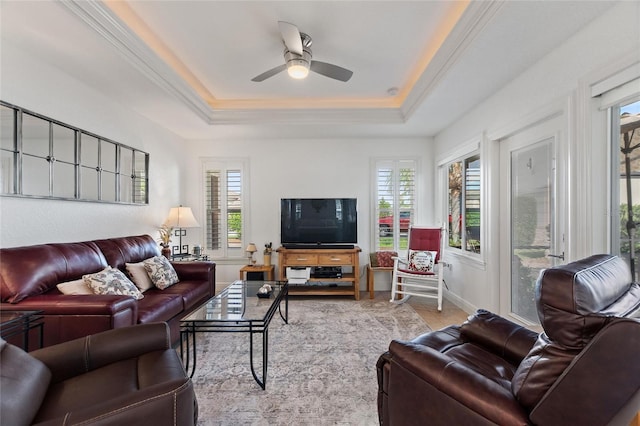 living room with ornamental molding, ceiling fan, and a tray ceiling