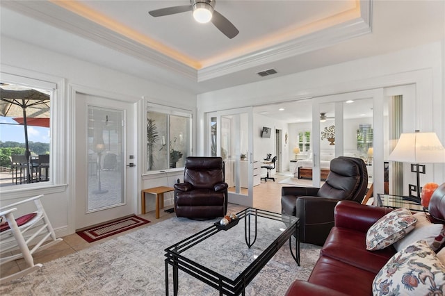 living room featuring light tile patterned floors, a tray ceiling, french doors, and ceiling fan