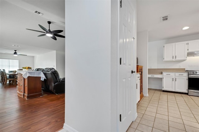 kitchen with white cabinetry, ceiling fan, stainless steel range oven, and light wood-type flooring