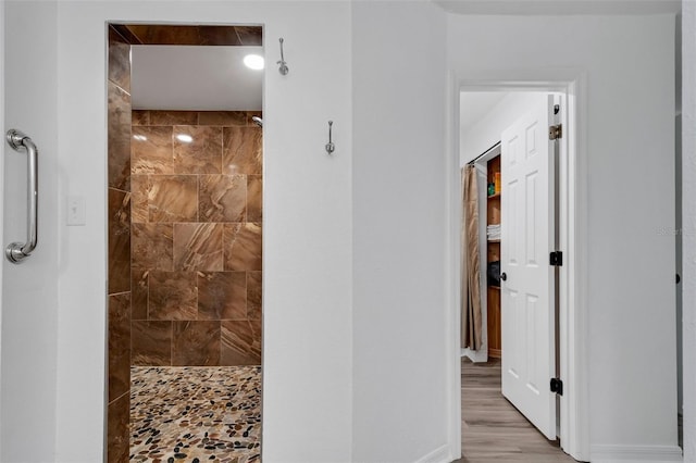 bathroom with tiled shower and hardwood / wood-style flooring