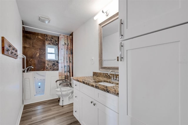 full bathroom featuring hardwood / wood-style floors, vanity, toilet, shower / bath combo with shower curtain, and a textured ceiling