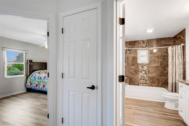 full bathroom featuring hardwood / wood-style floors, toilet, ceiling fan, and shower / bath combination with curtain