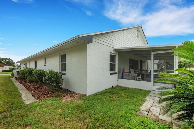 rear view of house with a lawn and a sunroom