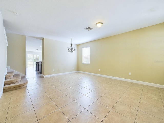 tiled empty room featuring a chandelier and a healthy amount of sunlight