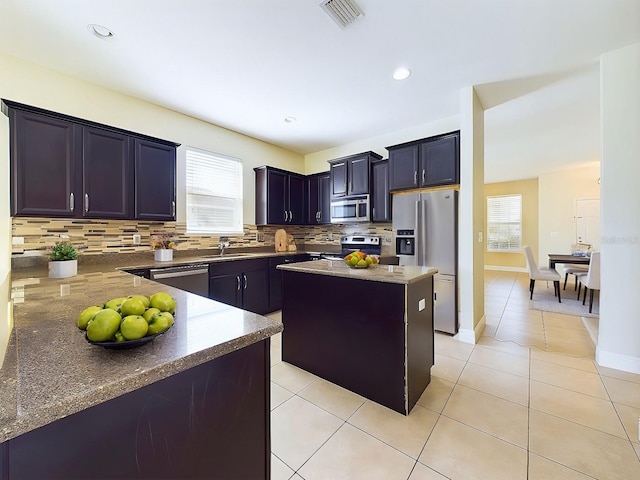 kitchen with appliances with stainless steel finishes, tasteful backsplash, a kitchen island, and a wealth of natural light