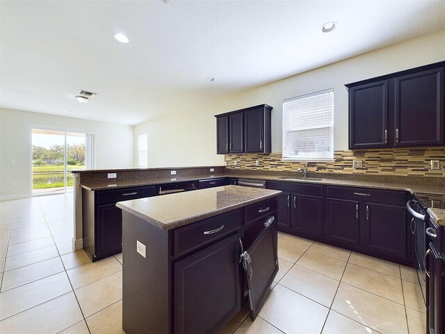 kitchen featuring decorative backsplash, sink, light tile patterned floors, dark stone countertops, and a center island