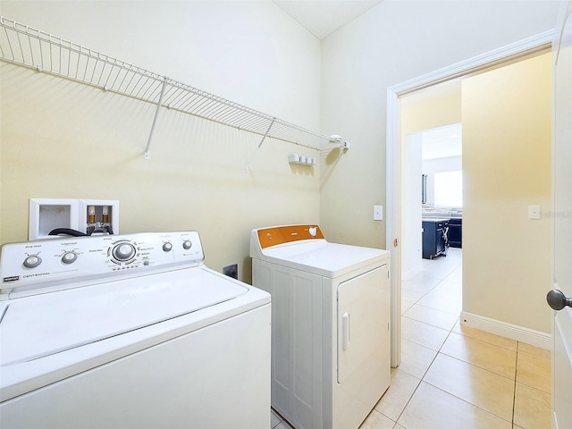 clothes washing area featuring light tile patterned floors and washing machine and clothes dryer