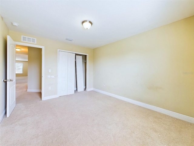 unfurnished bedroom with a closet and light colored carpet