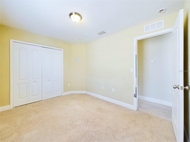 unfurnished bedroom featuring light carpet and a closet