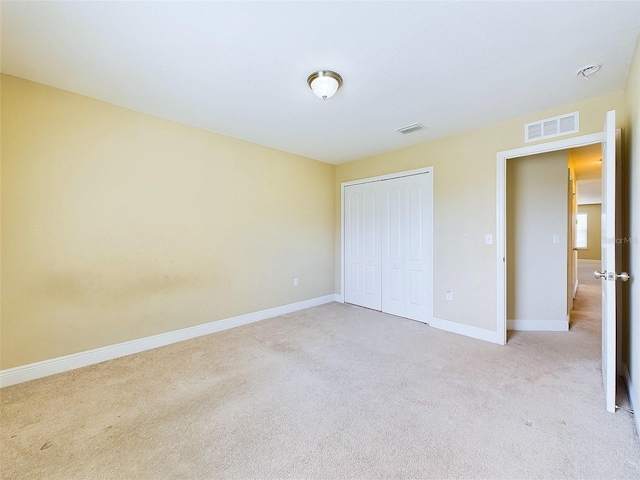 unfurnished bedroom featuring light colored carpet and a closet