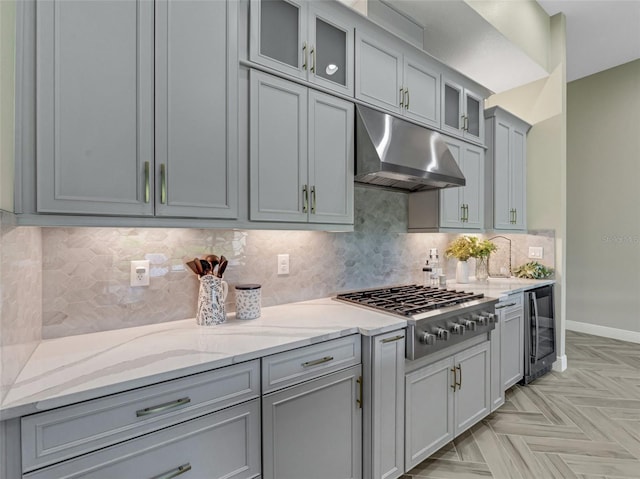 kitchen with light stone countertops, beverage cooler, stainless steel gas cooktop, backsplash, and light parquet floors