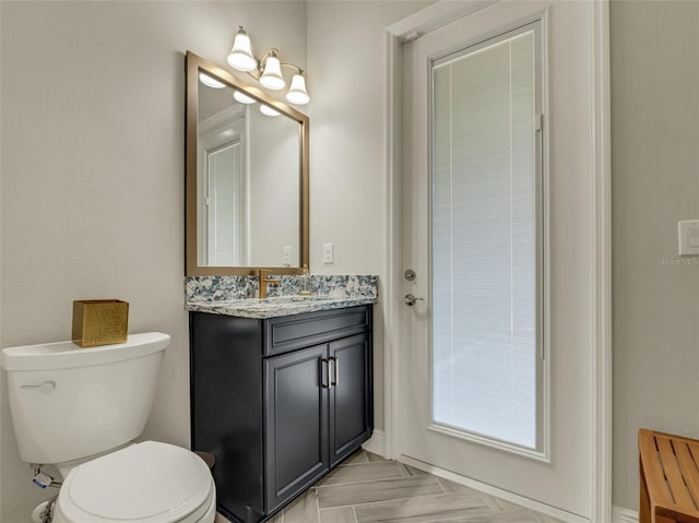 bathroom featuring parquet flooring, vanity, and toilet