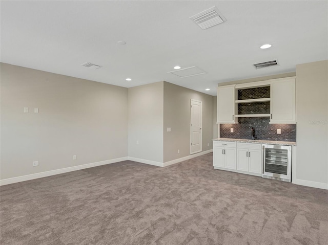 bar with beverage cooler, light stone counters, backsplash, carpet floors, and white cabinets