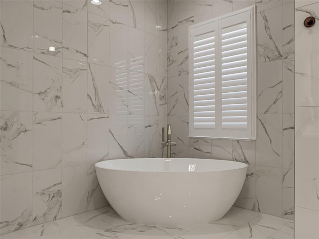 bathroom with a bathing tub and tile walls