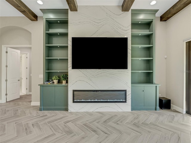 unfurnished living room with beam ceiling, built in shelves, and light parquet flooring