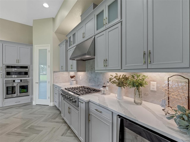 kitchen featuring decorative backsplash, light stone countertops, light parquet floors, and appliances with stainless steel finishes