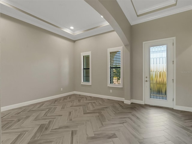 foyer entrance featuring a tray ceiling, a wealth of natural light, light parquet flooring, and ornamental molding