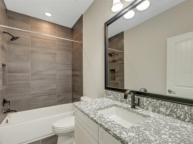 full bathroom featuring vanity, tiled shower / bath combo, and toilet