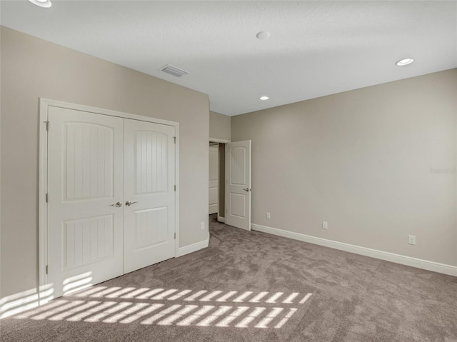 unfurnished bedroom with light carpet and a closet