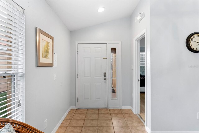 entryway with light tile patterned flooring and vaulted ceiling