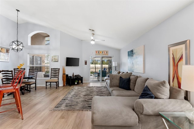 living room featuring ceiling fan with notable chandelier, light hardwood / wood-style floors, and vaulted ceiling