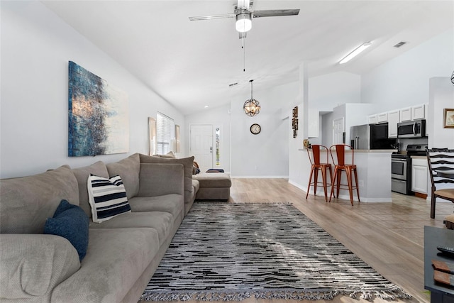 living room featuring ceiling fan, light hardwood / wood-style floors, and lofted ceiling