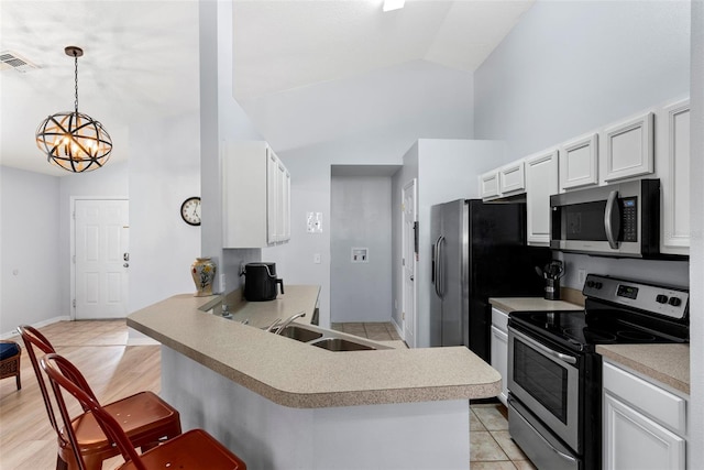 kitchen with pendant lighting, lofted ceiling, a kitchen breakfast bar, appliances with stainless steel finishes, and kitchen peninsula